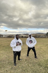 two men standing in a field with a cloudy sky