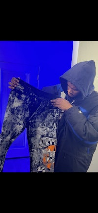 a man in a hoodie holding a pair of pants