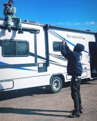 two men standing on top of an rv